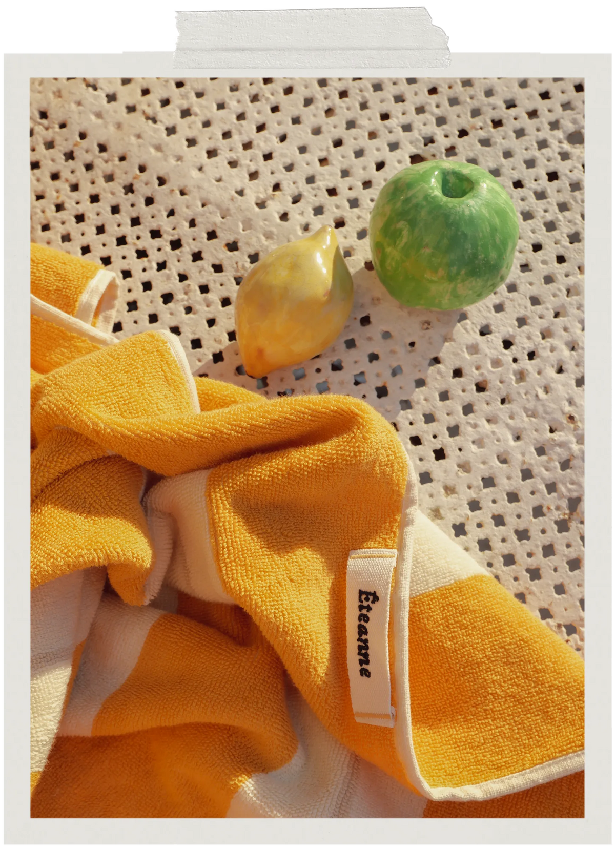 Éteanne striped beach towel in Tuscan Sun with green and yellow ceramic objects