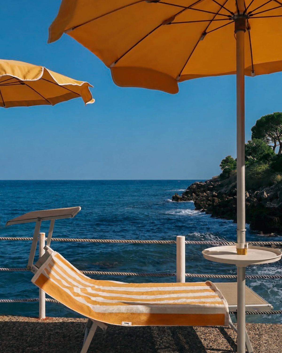 Éteanne striped beach towel in Tuscan Sun on sun bed by the Mediterranean Sea