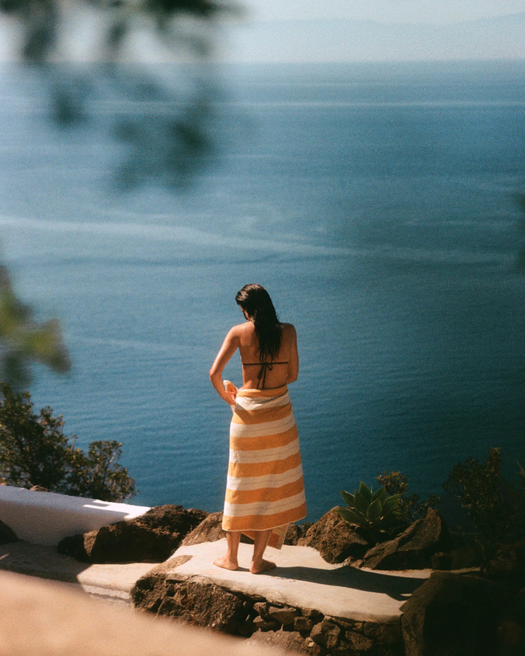 Woman wrapped in the Anne Beach Towel in Tuscan Sun overlooking the Mediterranean coastline.