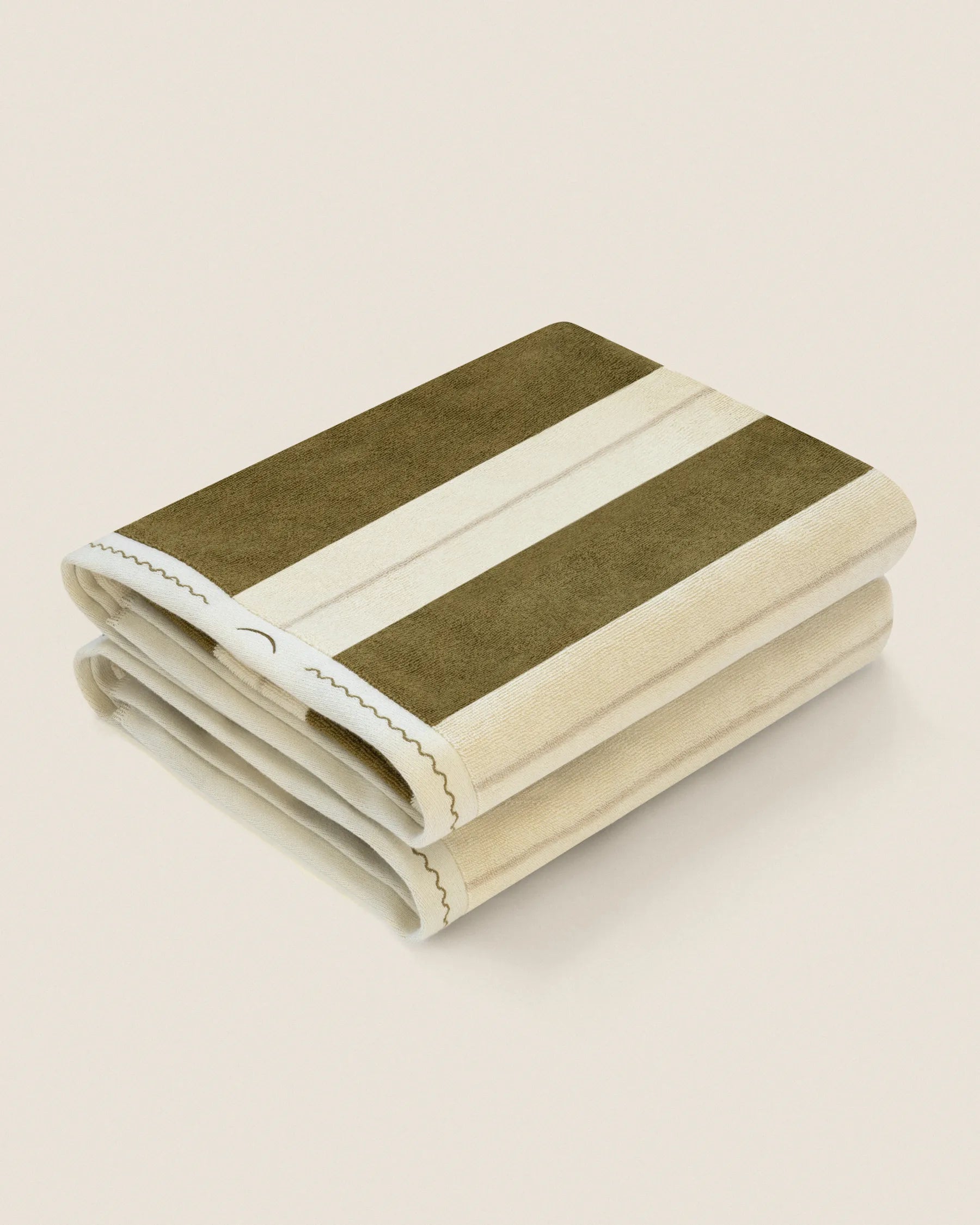 Folded pair of Éteanne Anné striped beach towel in Terre Verte on neutral background