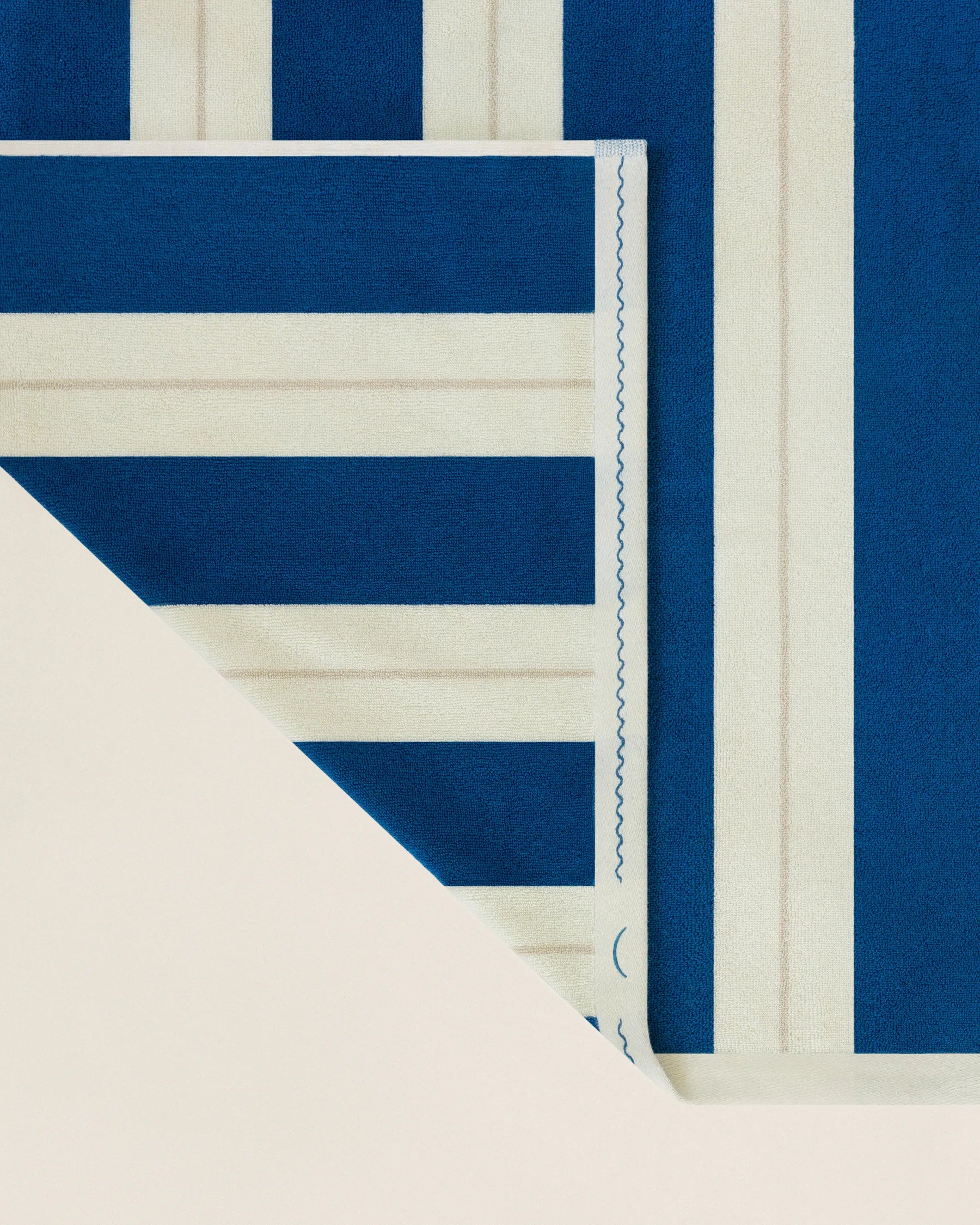 Folded striped beach towel in ora blu and ionian pearl showing thickness and softness