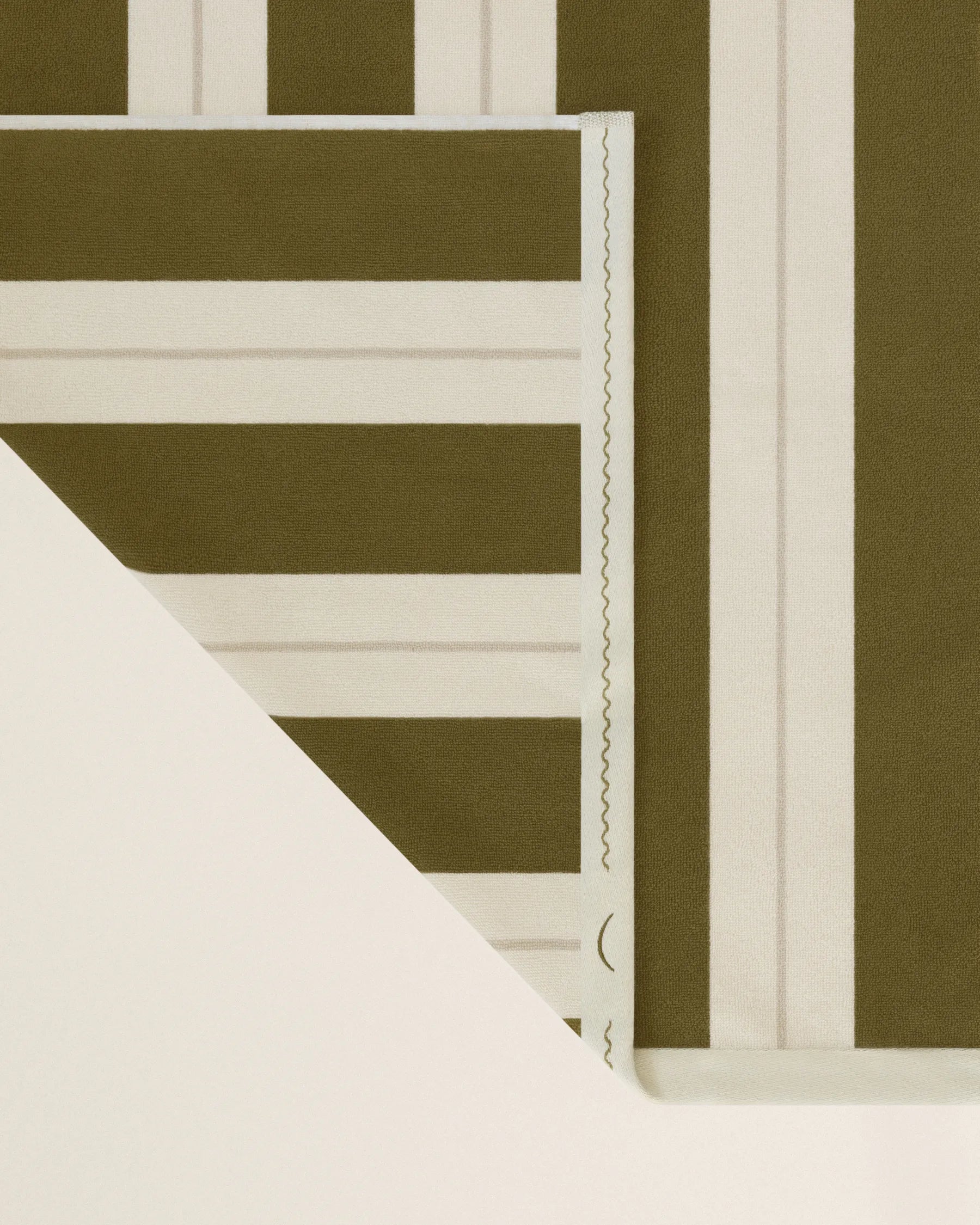 Folded striped beach towel in terre verte and ionian pearl showing thickness and softness