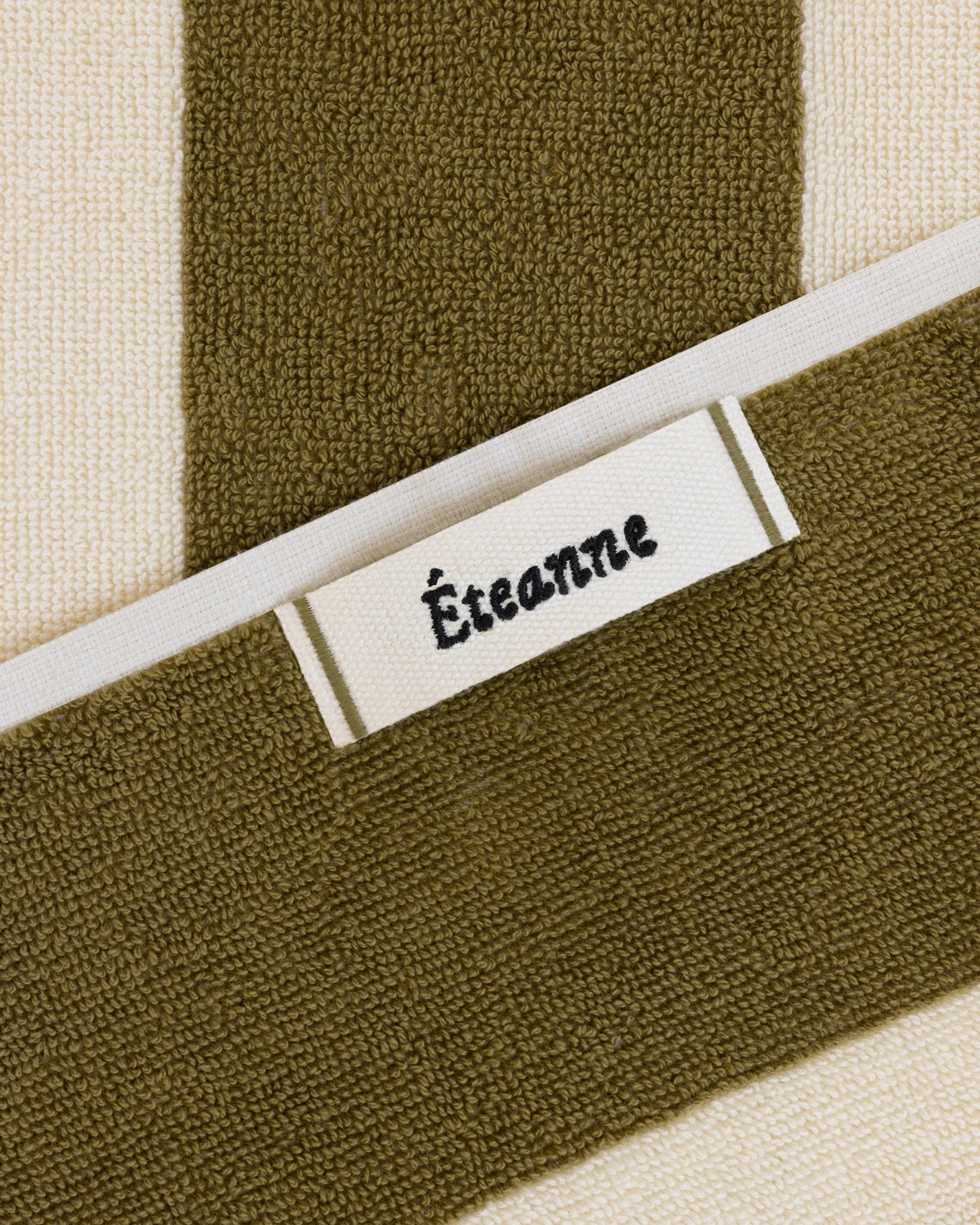 Éteanne woven label embroidered onto striped cotton beach towel in Terre verte color