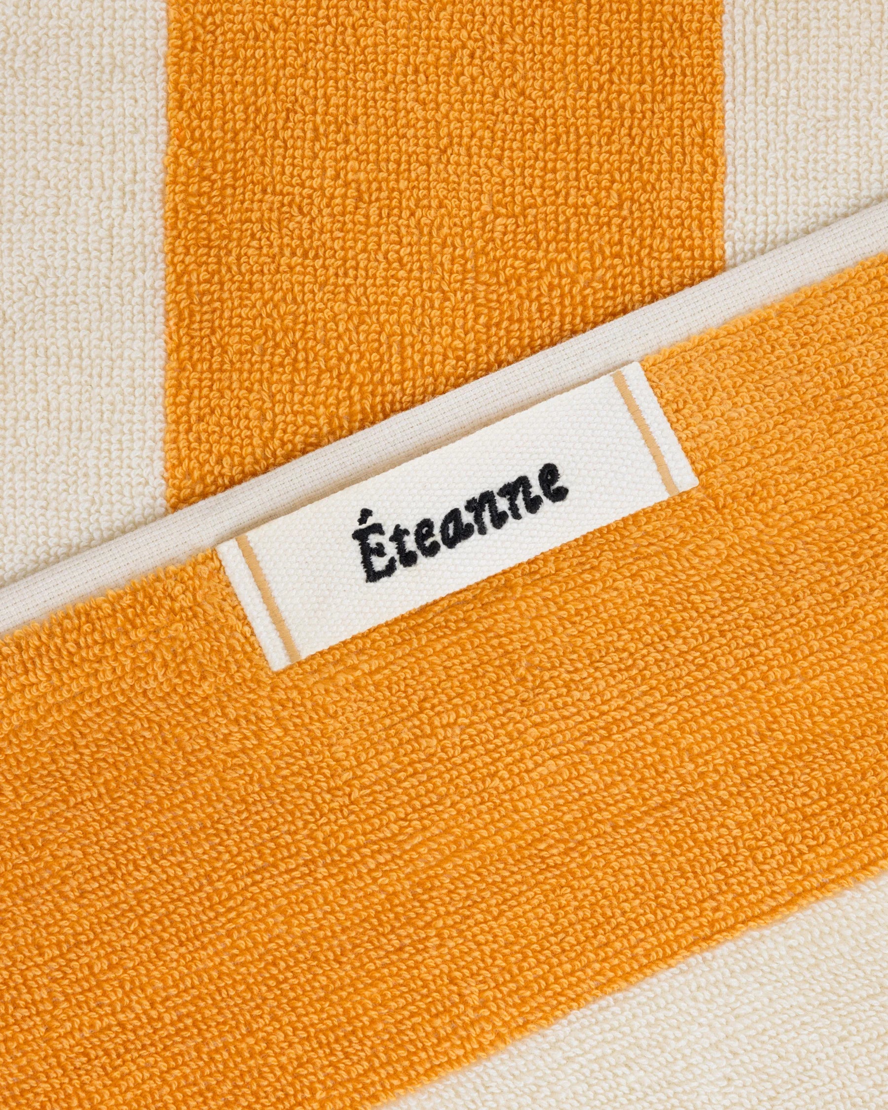 Éteanne woven label embroidered onto striped cotton beach towel in Tuscan Sun color