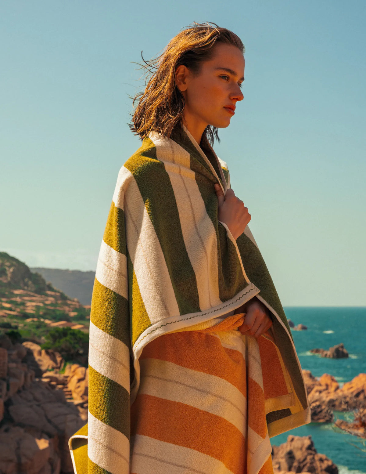 Woman wrapped in Éteanne striped beach towel in Terre Verte and Tuscan Sun.