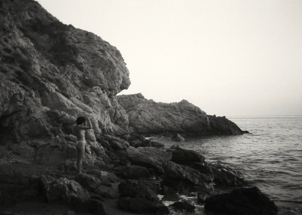 Alexandria Coe walking along a rocky Mediterranean coastline