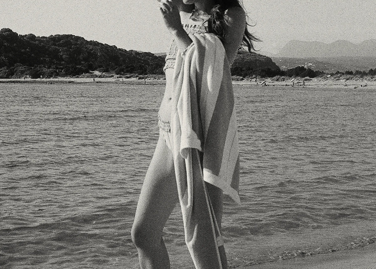 Alexandria Coe wrapped in an Éteanne Anné striped beach towel by the sea