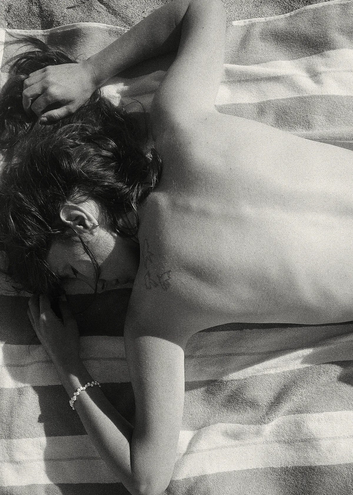 Alexandria Coe resting on an Éteanne Anné striped beach towel