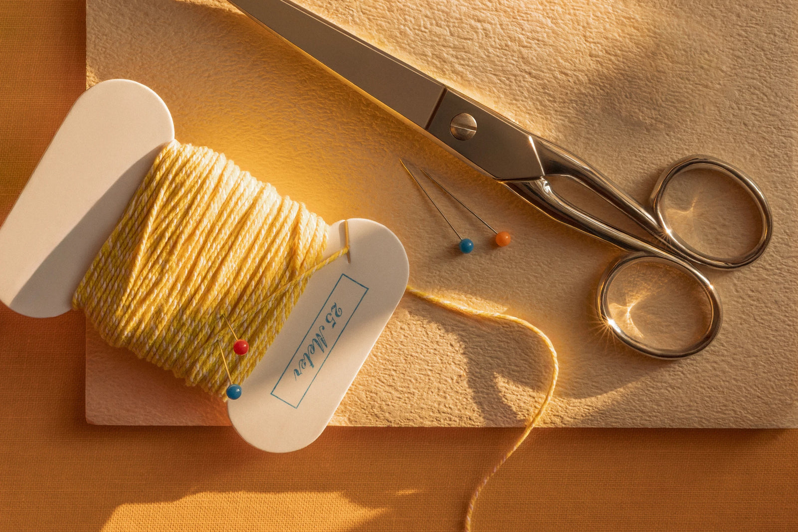 Yellow weaving yarn, scissors, and sewing pins in the Éteanne atelier.