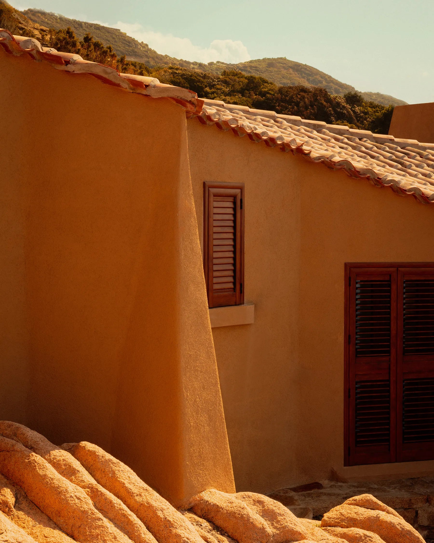 Exterior of Casa Scalesciani by Alberto Ponis with terracotta roof tiles and granite rocks in Costa Paradiso, Sardinia.
