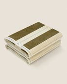 Folded pair of Éteanne Anné striped beach towel in Terre Verte on neutral background