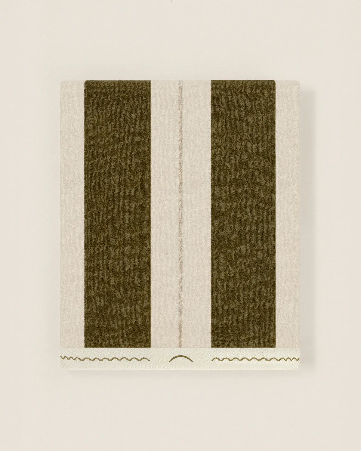 Folded striped Éteanne beach towel in green and ivory tones showing thickness and softness