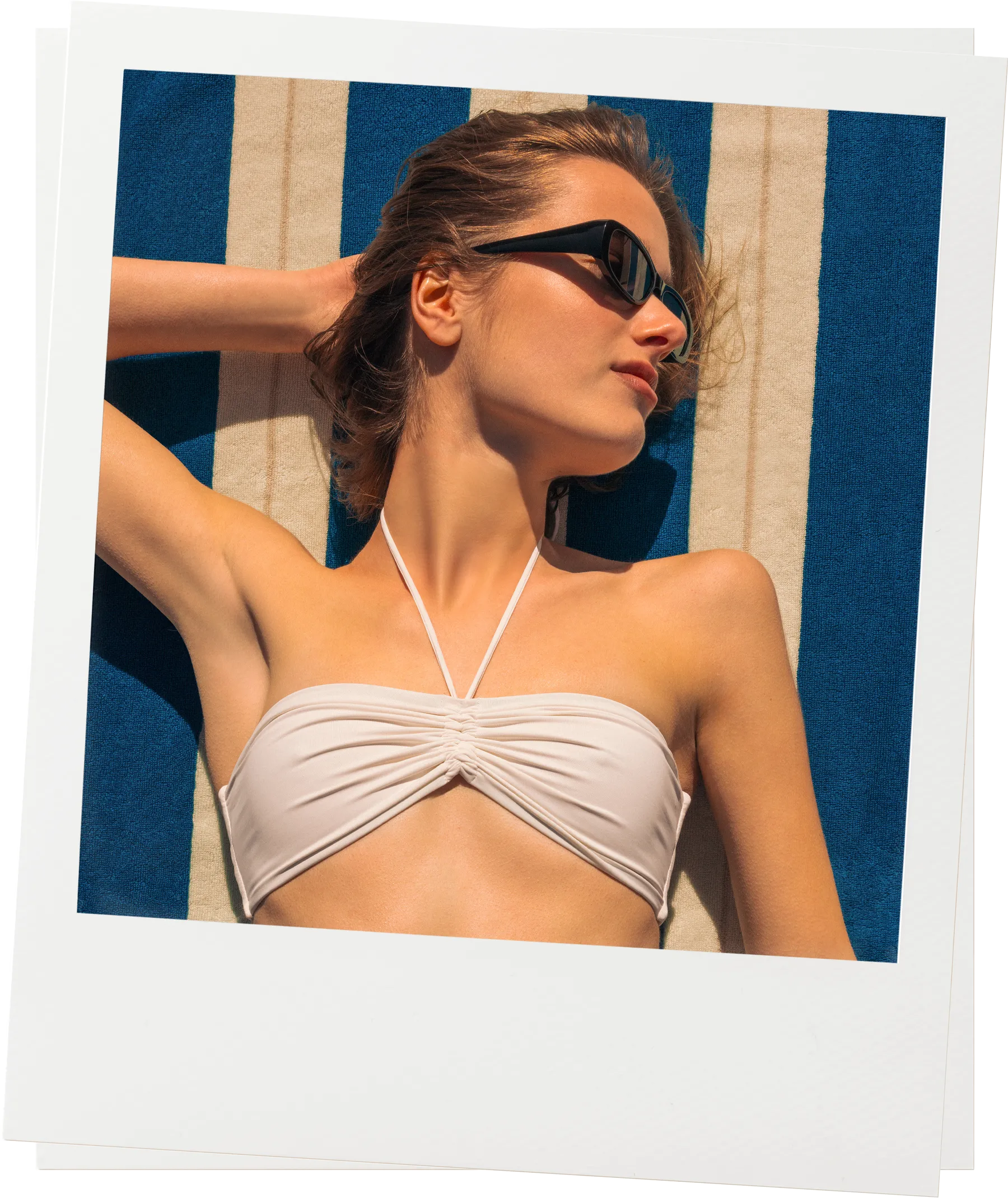 Woman relaxing on Éteanne Anné striped beach towel in Ora Blu by the sea