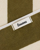 Éteanne woven label embroidered onto striped cotton beach towel in Terre verte color