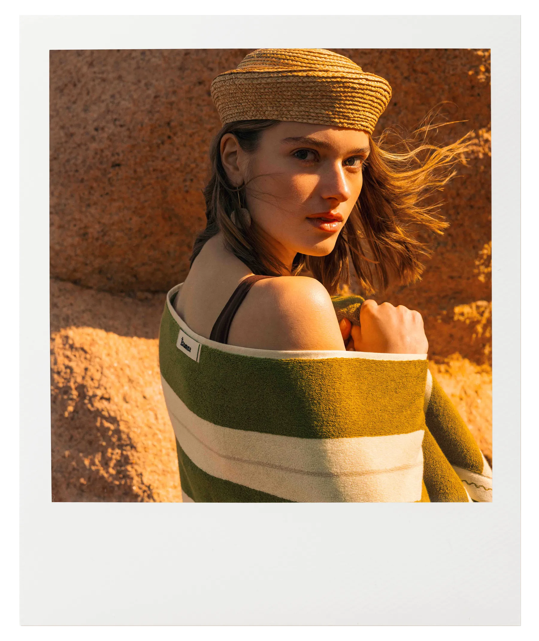 Woman wrapped in Éteanne Anné striped beach towel in Terre Verte in warm sunlight