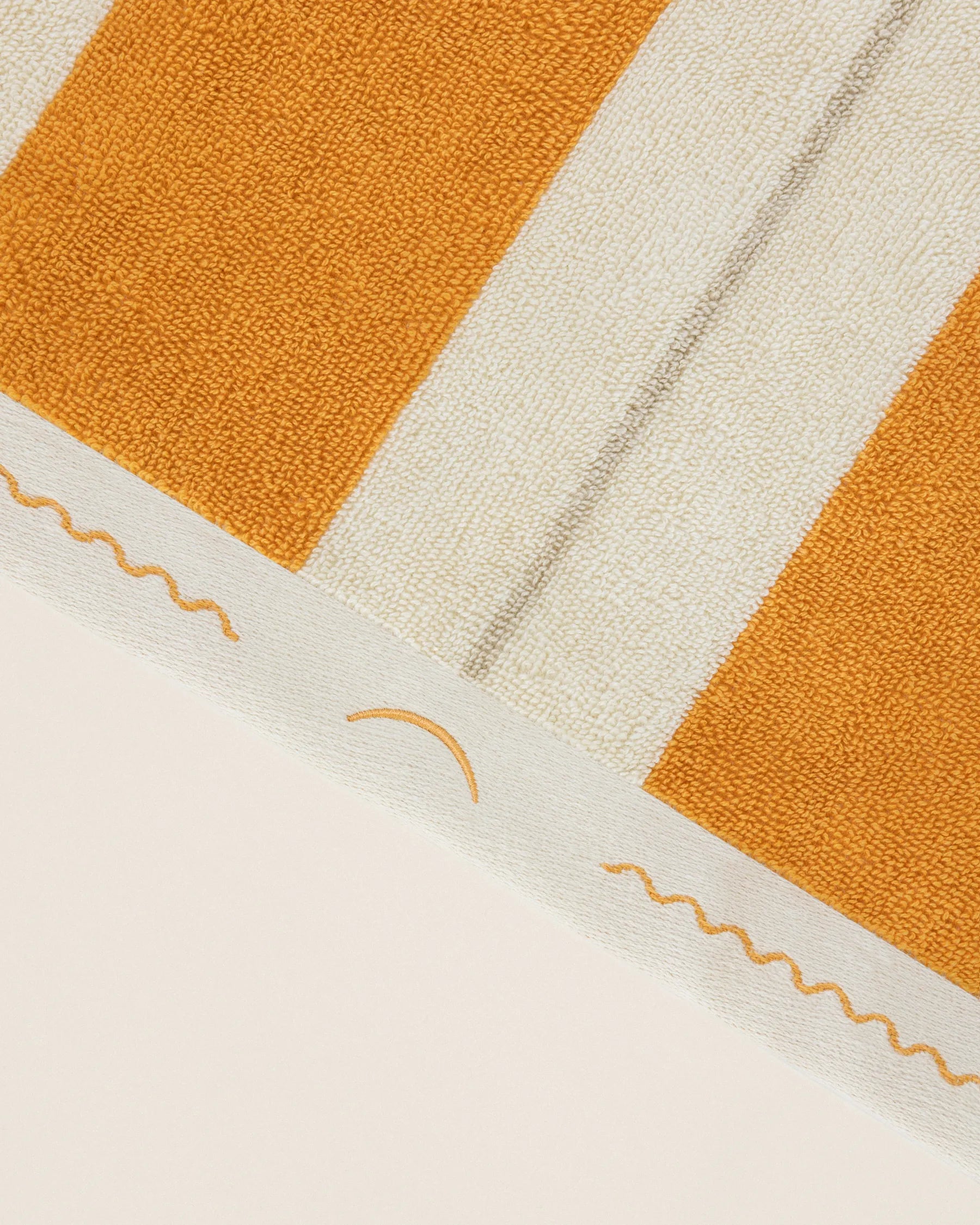 Close-up of striped beach towel edge with embroidered monogram in Tuscan sun and Ionian Pearl