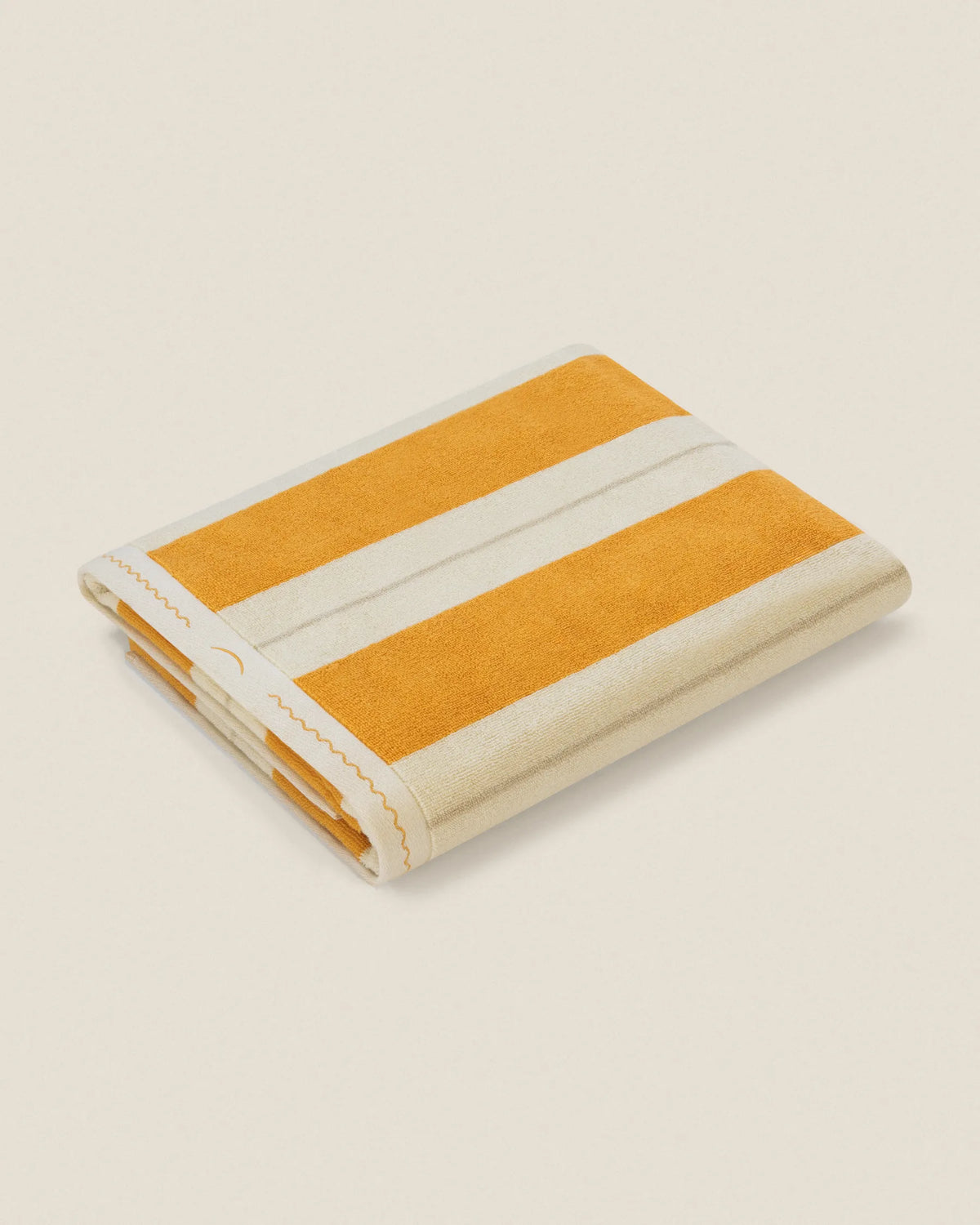 Folded Éteanne Anné striped beach towel in Tuscan Sun on neutral background