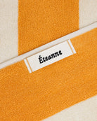 Éteanne woven label embroidered onto striped cotton beach towel in Tuscan Sun color