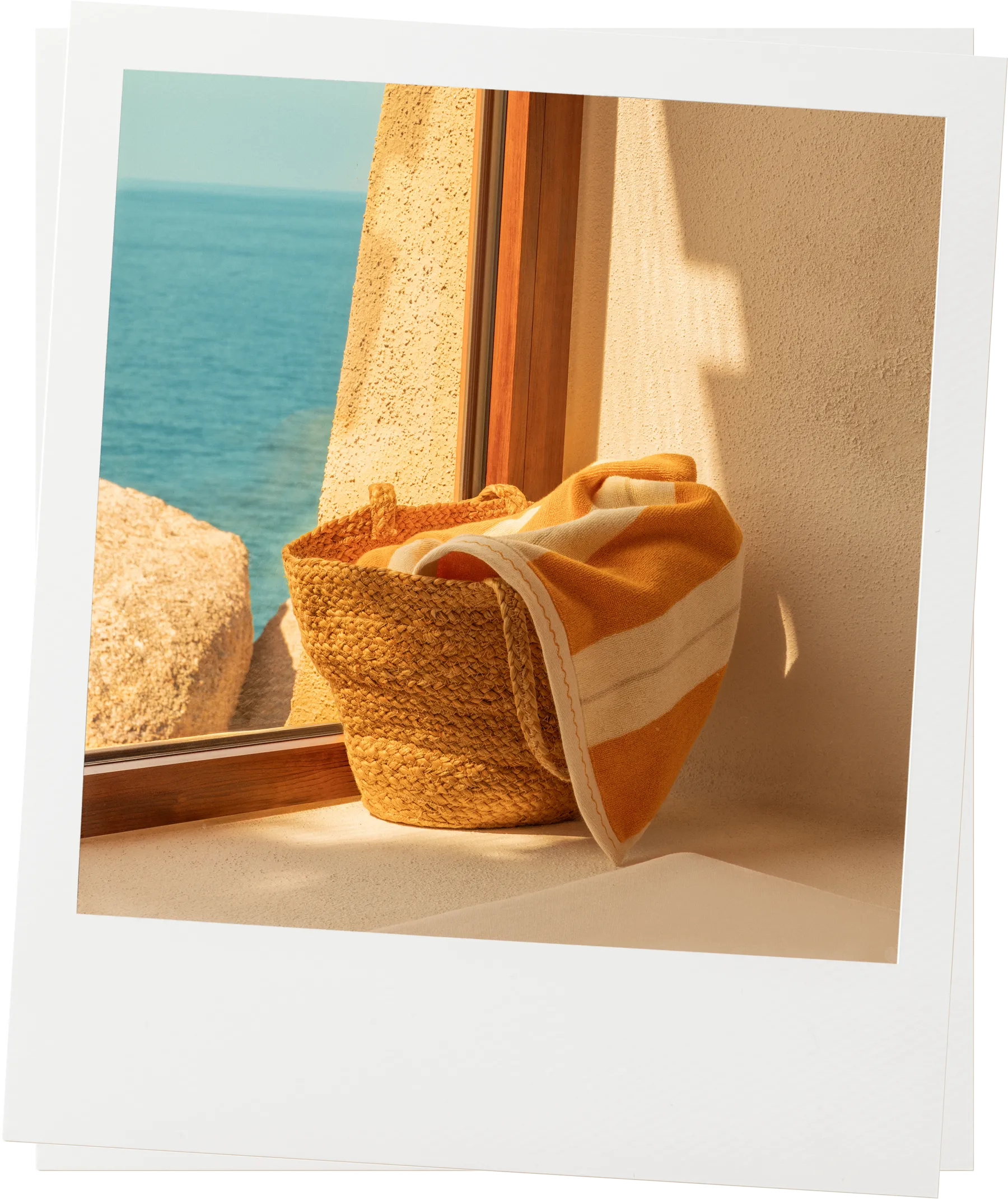 Éteanne Anné beach towel in Tuscan Sun placed in woven basket by window with sea view