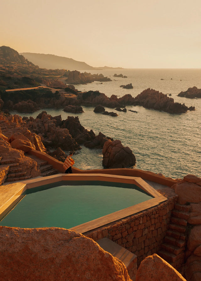 Mediterranean coastline at sunset with infinity pool and warm golden light