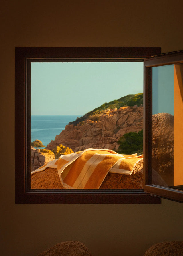 Éteanne Anné striped beach towel in Tuscan Sun displayed by open window